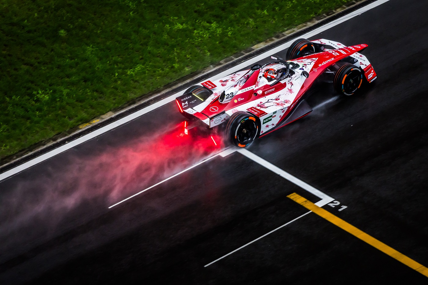 Aerial/rear shot of Norman Nato on-track in the #23 car with spray coming up from the wet track behind